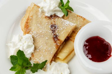 Kremalı krep, nane ve böğürtlen soslu beyaz tabak. Geleneksel Avrupa kahvaltısı. Yakın plan..