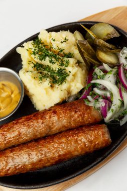 Patates püresi ve kızarmış sosis. Demir bir tavada ağız sulandıran geleneksel bir yemek. Yakın plan. Dikey.