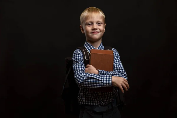 リュックと本を手に笑顔の少年 7歳の子供は青いシャツを着ています 学校に戻る 勉強と教育 黒の背景 — ストック写真