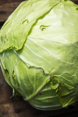 Tahta bir masada taze lahana başı. Yeni mevsimlik sebze hasadı. Doğadan gelen sağlık. Yakın plan. Dikey.
