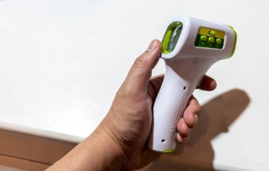 Beyaz arkaplanda beyaz ve yeşil kızılötesi termometre var.