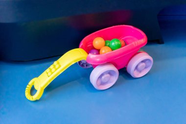 Mavi arka planda renkli toplar içeren renkli plastik oyuncak araba.