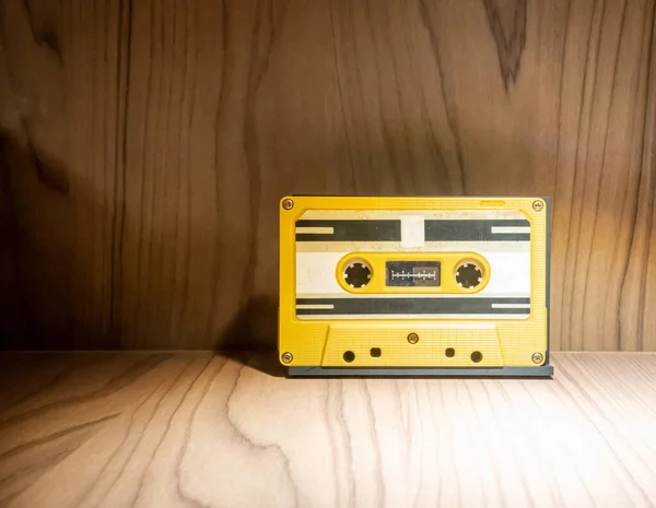 木製の背景に黄色のプラスチックケースに古いと汚れたヴィンテージのオーディオテープカセットの閉鎖 — ストック写真