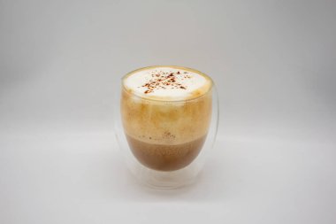 Sütlü, köpüklü, sütlü kahve beyaz arka planda izole edilmiş çift camlı dekorasyon için kakao gücü serpiştirilmiş..