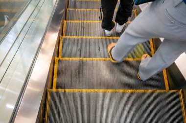 Yürüyen ayaklar yürüyen merdivende. Ulaşım ve dolaşım kavramı.