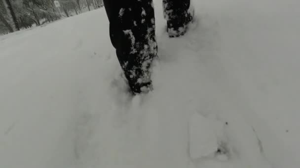 Hombre caminando en la nieve con pantalones negros y botas — Vídeo de stock