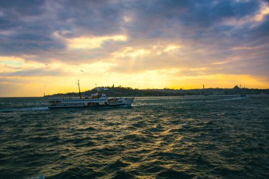 İstanbul şehir manzarası ve gün batımında bir feribot. İstanbul arka plan fotoğrafı. İstanbul feribot hattı arka planda. İstanbul Boğazı ve İstanbul.