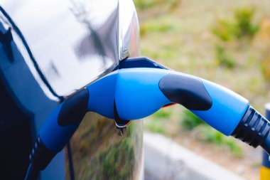 Hızlı EV şarj cihazını siyah EV vagonuna taktım. Yüksek kalite fotoğraf. EV araba şarj aleti. Geleceğin teknolojisi. Sıfır emisyon arabası. Karbonsuz. 