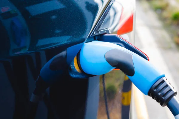 Plugged in Fast EV Charger to the black EV car in focus. High quality photo. EV car charger. Future technology. Zero emission car. Carbon free.