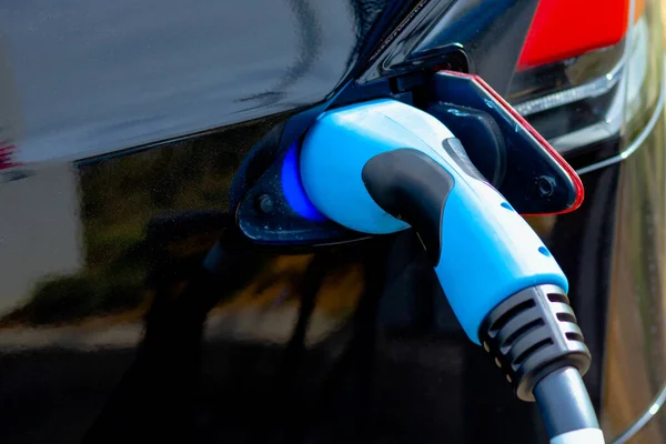 Hızlı EV şarj cihazını siyah EV vagonuna taktım. Yüksek kalite fotoğraf. EV araba şarj aleti. Geleceğin teknolojisi. Sıfır emisyon arabası. Karbonsuz. 