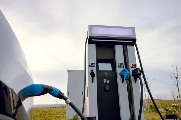 EV car plugged in charger and EV Charger station. Electric car charger station near the highway. Electric car. Zero emission car charging. Carbon free