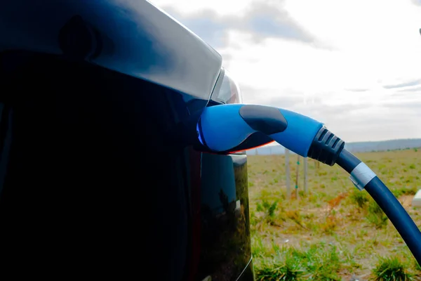 Plugged in Fast EV Charger to the black EV car in focus. High quality photo. EV car charger. Future technology. Zero emission car. Carbon free.