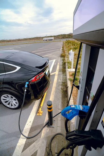 Electric vehicle charging near the EV charging station. Zero emission cars. EV chargers. Alternative energy. Fast AC EV chargerer. Plugged in electric car on the station.