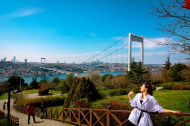 İstanbul hindi - 3.29.2021: İstanbul 'da Fatih Sultan Mehmet Köprüsü' ne karşı fotoğraf çeken güzel genç bir kadın. Otagtepe Fatih Ormanı. 