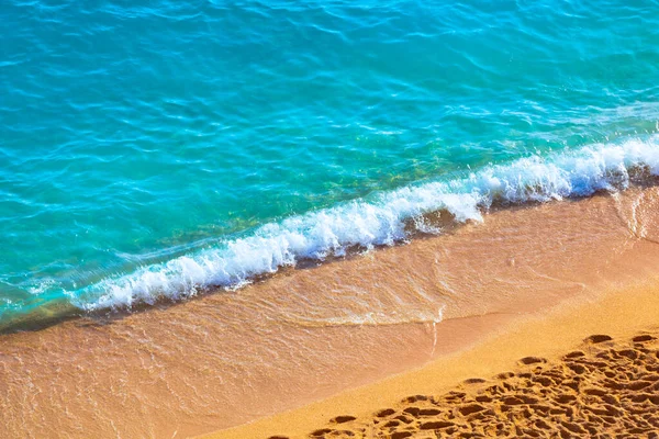 Ένα κύμα γαλαζοπράσινης θάλασσας και όμορφης παραλίας με πατημασιές. — Φωτογραφία Αρχείου