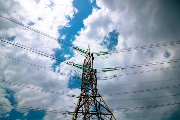 Electricity transmission towers or pylons with cables and cloudy sky.