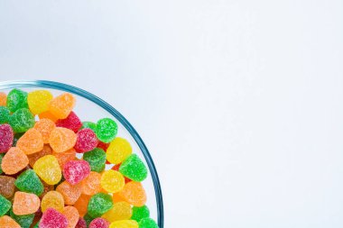 Fotokopi alanı olan beyaz arka planda izole edilmiş kasede çok renkli jöle şekerler var. Lezzetli marmelatlar kasede. 