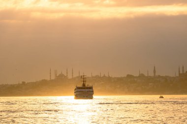 İstanbul kenti, gün batımında İstanbul feribot ve şehir manzarasına sınır çiziyor.
