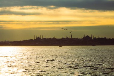 Gün batımında, bulutlu gökyüzü ve güneş ışınlarıyla İstanbul 'un silueti. İstanbul arka plan fotoğrafı. İstanbul şehri Kadıköy 'den.