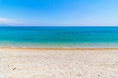 Kumsalda çakıl taşları ve açık mavi gökyüzüne karşı turkuaz deniz. Yaz, tatil, tatil, sahil, deniz kenarı. Akdeniz.