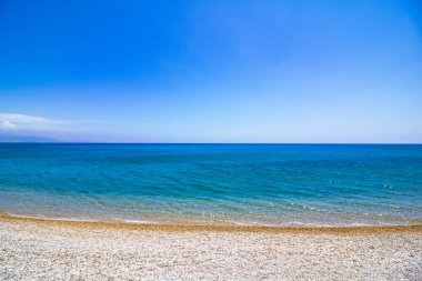 Kumsalda çakıl taşları ve açık mavi gökyüzüne karşı turkuaz deniz. Yaz, tatil, tatil, sahil, deniz kenarı. Akdeniz.