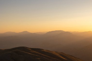 Gün batımında, bulutlu ve açık gökyüzüyle dağ sırasının manzarası. Gün batımı görünümü.