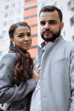 Yeni apartmanın önünde yeni evli bir çift. Dikey çerçevelenmiş çekim.