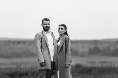 Doğanın arka planında gri ceketli şık bir çift. Mutlu şehvetli düğün çifti. Yeni evlilerin romantik anları. Yatay çerçeveli çekim.