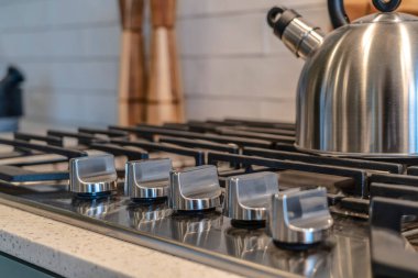 Beş düğmeli fırın ve ocağın tepesinde dökme demir ızgara ile çaydanlık.