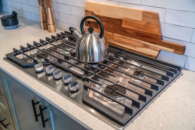 Tencerenin tepesindeki çaydanlık ahşap kesim tahtasına ve fayans arkaplanına karşı.