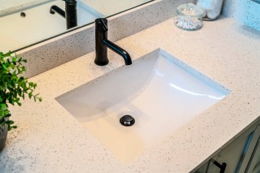 Tek lavabo ve siyah musluk banyo tezgahının üzerine inşa edilmiş.