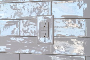 Evin beyaz kiremit duvarına karşı üç yuvası olan topraklanmış priz.