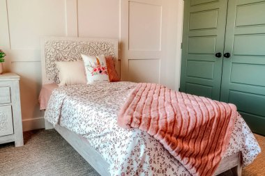 Çiçekli yatak ve beyaz panelli duvara karşı dekoratif yatak başlığı.