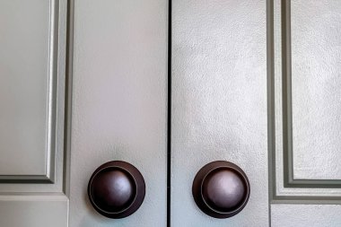 Ahşap panelli çift kapılar üzerine kurulmuş parlak yuvarlak siyah kapı tokmakları.