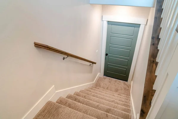 Stairway inside home with U shape design and leads to the wooden basement door