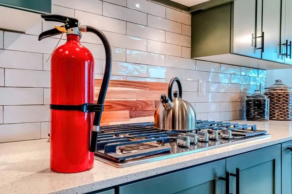 Extintor de incendios y encimera con hervidor de agua en la encimera dentro de la cocina casera — Foto de Stock