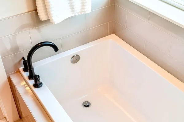 Rechthoekig gebouwd bad met zwarte gebogen kraan in de badkamer van thuis — Stockfoto
