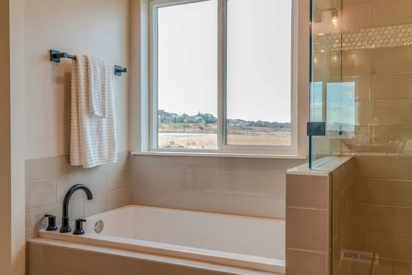 Built in rectangular bathtub and glass wall shower stall inside bathroom of home