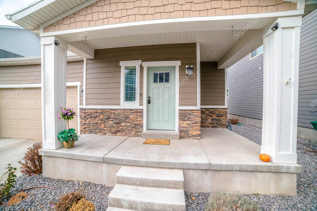 Front door and sidelight against brick wall and wood siding of home with porch