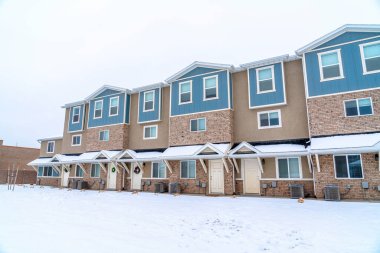Karlı ve bulutlu gökyüzü olan bir mahalle manzarasında üç katlı apartman.