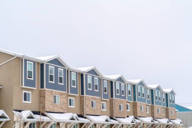 Karlı çatıları olan bir apartmanın üzerinde bulutlu bir gökyüzü olan bir mahallede kış.