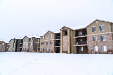Balkonları ve karlı çatıları olan üç katlı tuğladan bir apartman.