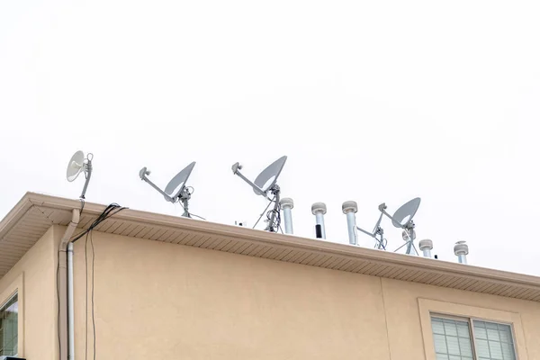 Antenas parabólicas no telhado do edifício residencial contra o céu nublado — Fotografia de Stock