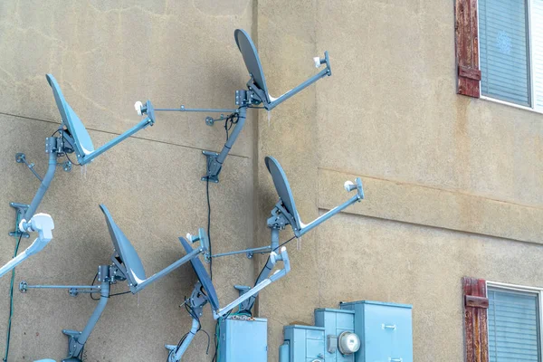 Спутниковые тарелки и электросчетчики установлены на стене жилого дома — стоковое фото