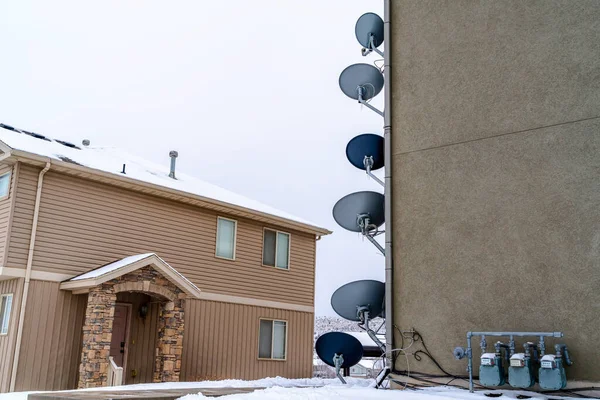 Parabolické satelitní talíře a elektroměry na vnější stěně budovy — Stock fotografie