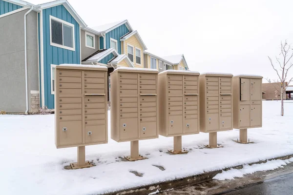 Ряд почтовых ящиков на снежной улице вдоль мокрой дороги в зимний период — стоковое фото