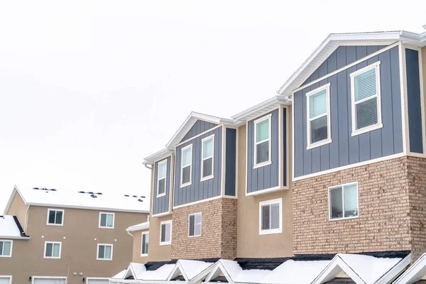 Plantas superiores de apartamentos y casas adosadas contra la nieve y el cielo nublado en invierno — Foto de Stock