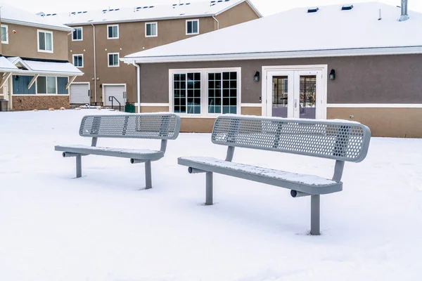 Zwei leere Bänke auf einem Park inmitten einer schneebedeckten Nachbarschaft — Stockfoto