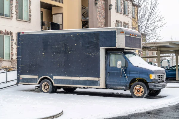 Commercial delivery truck parked in front of a residential building in winter