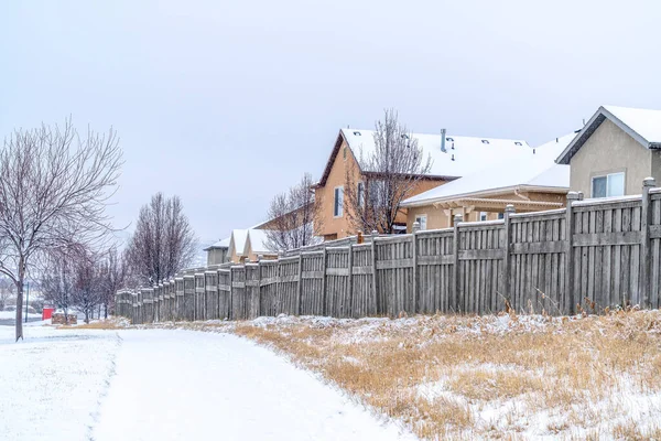 Lato strada innevata lungo recinzioni di legno di case in un bellissimo quartiere — Foto Stock